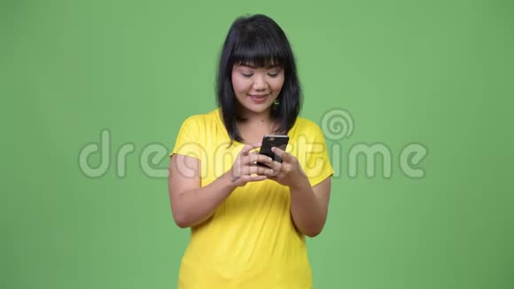 美丽快乐的亚洲女人用电话思考视频的预览图