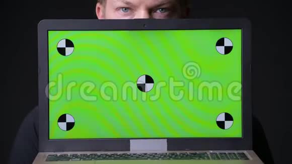 年轻的帅哥用带绿色屏幕色键的笔记本电脑视频的预览图