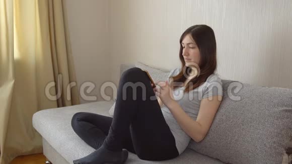 坐在沙发上打电话的年轻女子视频的预览图