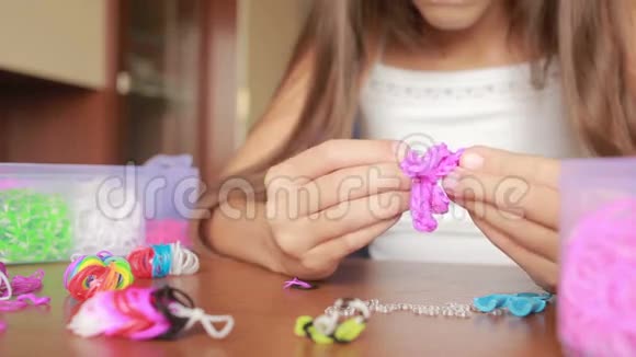小女孩编织橡皮筋的腕带编织的彩色橡皮筋视频的预览图