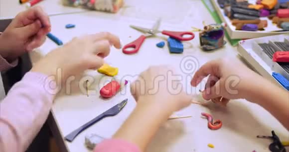 坐在办公桌前的可爱的小孩子从彩色造型塑料制成的图形中提取出不同的图形视频的预览图