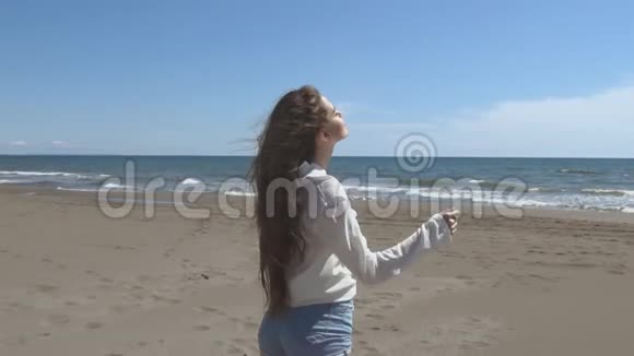 美丽的年轻少女头发挽起黑发在海滩上奔跑享受生活慢动作视频的预览图