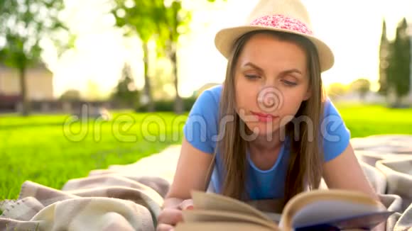 日落时分女孩在公园的毯子上躺着看书视频的预览图