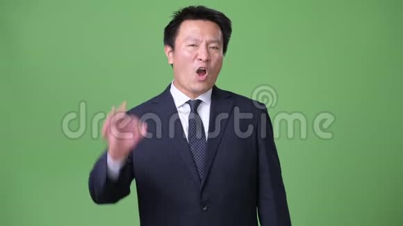 成熟的日本商人在绿色背景下视频的预览图