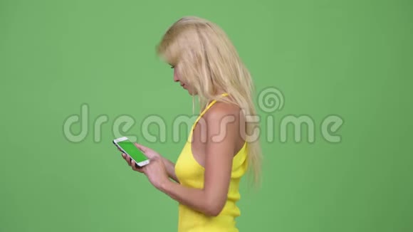 年轻漂亮的金发女人在绿色背景下使用电话视频的预览图