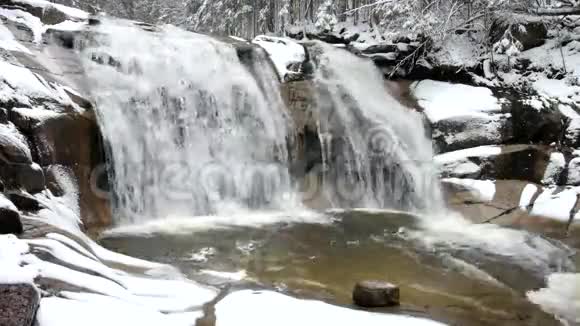 冬季瀑布小池塘和白雪皑皑的巨石瀑布层层叠叠山河的水晶冻水和声音视频的预览图