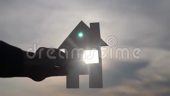 幸福家庭建设住宅理念他手里拿着一个纸房生活方式他的手在夕阳下剪影视频的预览图