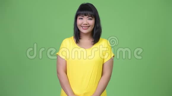 美丽快乐的亚洲女人在绿色的背景下微笑视频的预览图