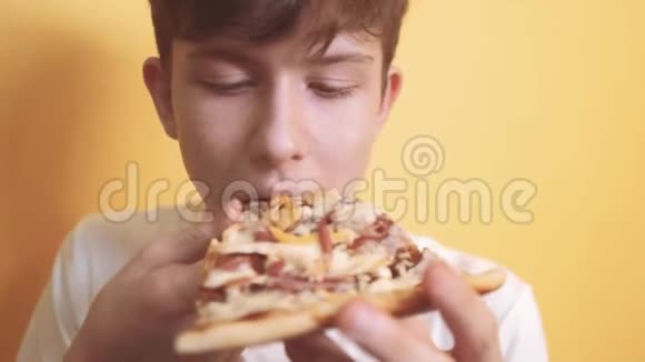 快乐的小男孩吃一片披萨的概念少年男孩饿了吃一片披萨慢动作视频比萨饼快视频的预览图