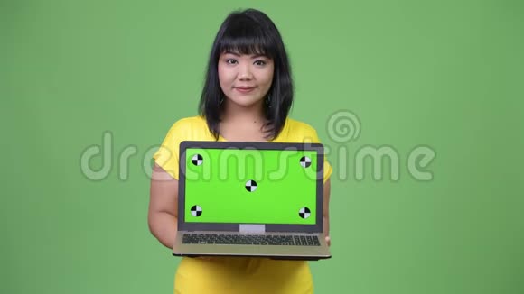美丽快乐的亚洲女人展示笔记本电脑视频的预览图