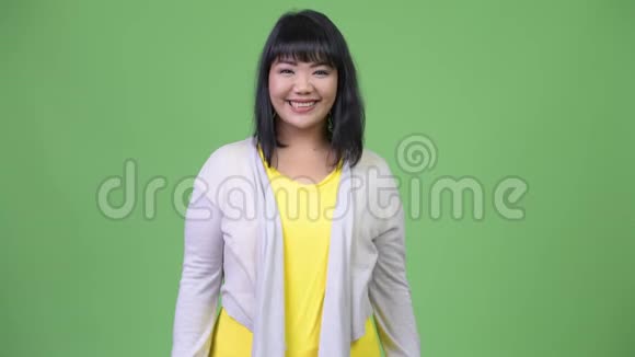 美丽快乐的亚洲女人在绿色的背景下微笑视频的预览图