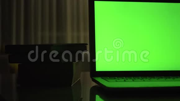 带有绿色屏幕的笔记本电脑黑暗的家庭办公室视频的预览图