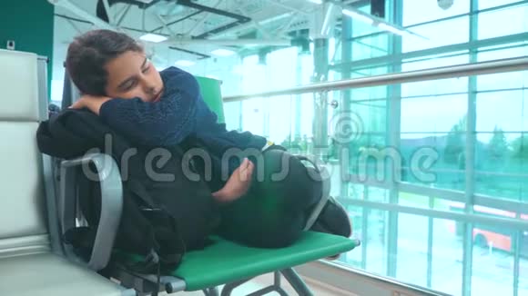 疲惫的少女少年旅行者睡在机场等待生活方式飞机起飞的大门和她所有的人坐在长凳上视频的预览图