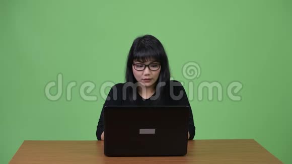 美丽的亚洲女商人用手提电脑思考视频的预览图