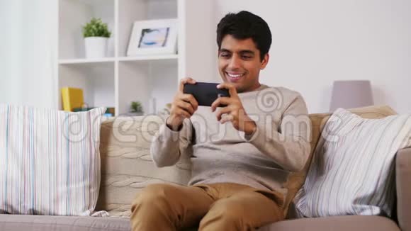 男人在家里玩智能手机游戏视频的预览图