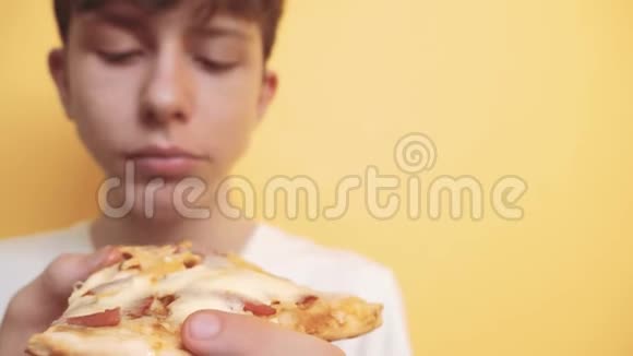 披萨快乐的小男孩吃一片披萨的概念饥饿的青少年男孩吃一片生活方式披萨慢动作视频的预览图