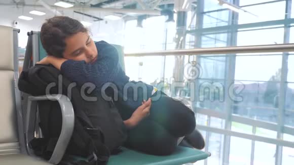 疲惫的少女少年旅行者睡在机场等待飞机起飞登机口的长椅上她的行李都在她身边视频的预览图