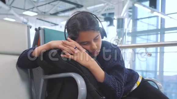 机场生活方式候机厅房间供飞机飞行戴着耳机听音乐的年轻快乐少女视频的预览图
