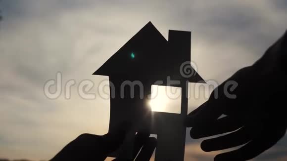 幸福家园建设理念他手里拿着一间纸房生活方式日落时的剪影视频的预览图