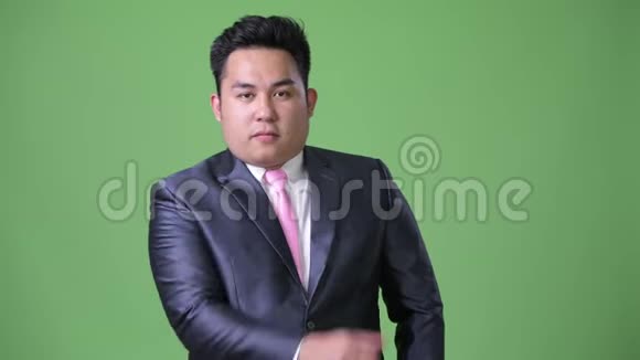 年轻英俊的超重亚洲商人绿色背景视频的预览图