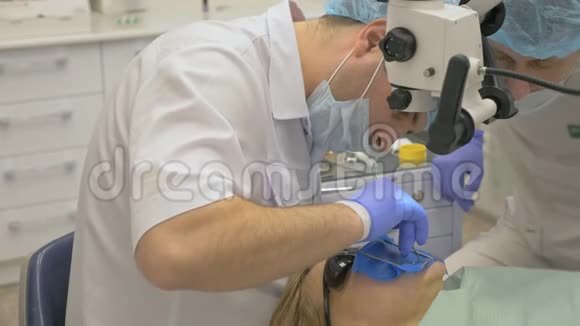 医生用过显微镜牙医在现代牙科诊所治疗病人正畸医生与助理一起工作行动视频的预览图