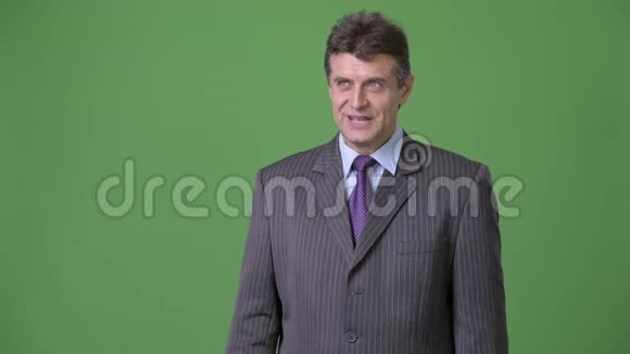 成熟英俊的商人在绿色背景下视频的预览图