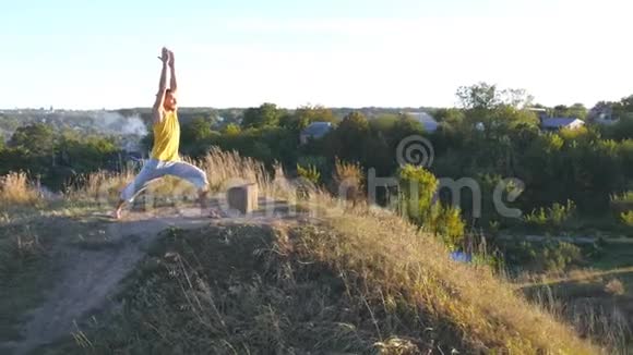 年轻的运动男子站在瑜伽姿势户外在大自然中练习瑜伽动作和姿势的白人运动员视频的预览图