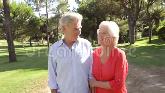 年长夫妇步行穿过公园交谈视频的预览图