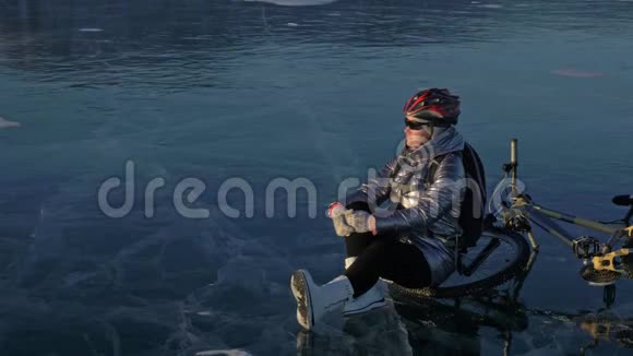 女人在冰上骑自行车女孩穿着银色羽绒服自行车背包和头盔这就是视频的预览图