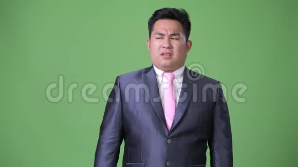 年轻英俊的超重亚洲商人绿色背景视频的预览图