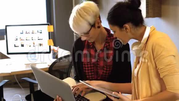 两位女商务主管在数码平板电脑和笔记本电脑上互动视频的预览图