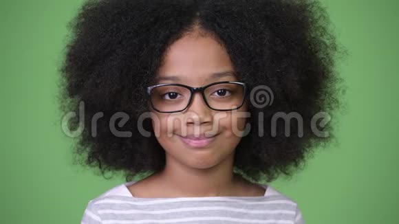 年轻快乐的非洲女孩非洲的头发在绿色的背景下微笑视频的预览图