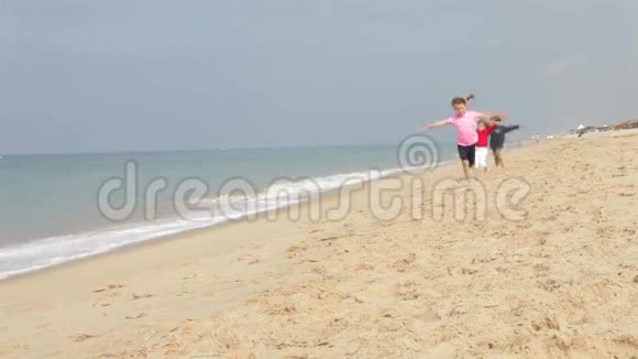 三个孩子一起沿着海滩奔跑视频的预览图