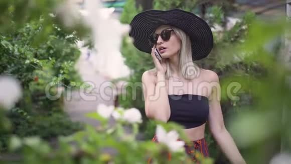 年轻时尚的漂亮女人戴着帽子使用智能手机女人在打电话视频的预览图