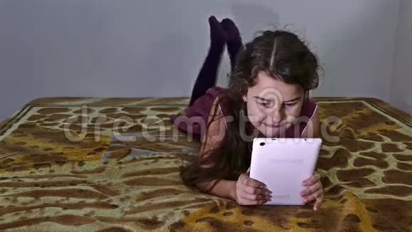 十几岁的女孩在床上玩平板电脑视频的预览图