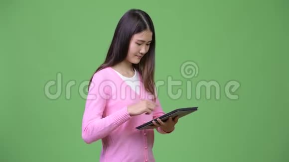 年轻漂亮的亚洲女人用数码平板电脑视频的预览图