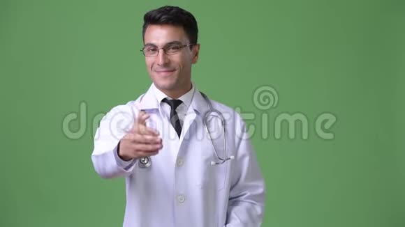 年轻英俊的西班牙男子医生绿色背景视频的预览图