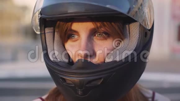 日落时分戴着头盔的年轻红发女子摩托车手的肖像视频的预览图