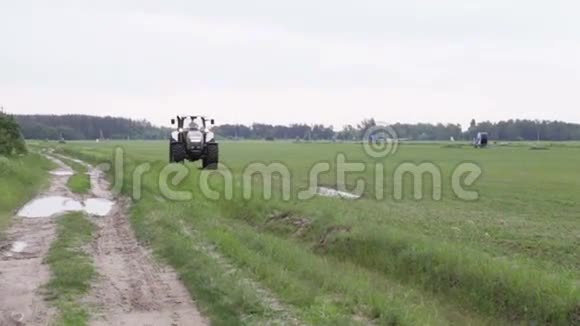 灰色拖拉机骑在绿色的田野上视频的预览图