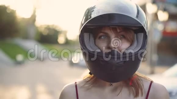 日落时分戴着头盔的年轻红发女子摩托车手的肖像视频的预览图