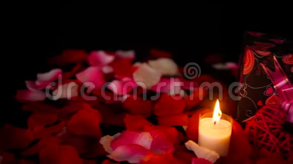 装饰镜头情人节礼物盒蜡烛燃烧和玫瑰花瓣视频的预览图