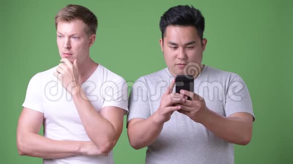 两个年轻的多民族帅哥在绿色背景下在一起视频的预览图
