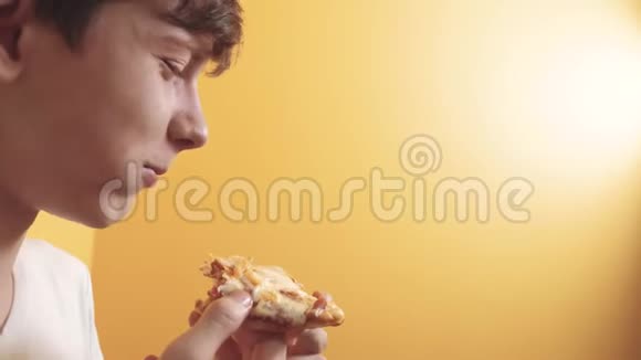 披萨快乐的青少年男孩吃一片比萨饼概念的生活方式十几岁的男孩饿了吃一片披萨慢动作视频的预览图