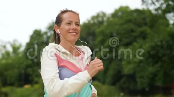有耳机的女人在公园里跑视频的预览图