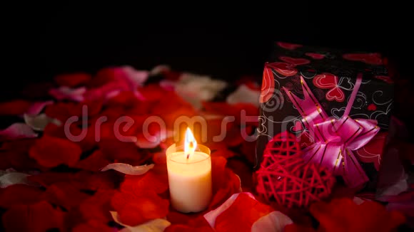 装饰镜头情人节礼物盒蜡烛燃烧和玫瑰花瓣视频的预览图