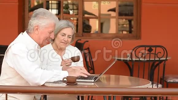 快乐的老夫妇坐在笔记本电脑旁视频的预览图
