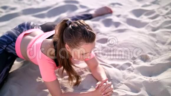 健康年轻的美女伸展身体在日出时在海滩上练习瑜伽锻炼身体以保持平衡视频的预览图