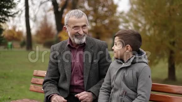 爷爷和孙子一起在公园里度过时光他们坐在长凳上视频的预览图