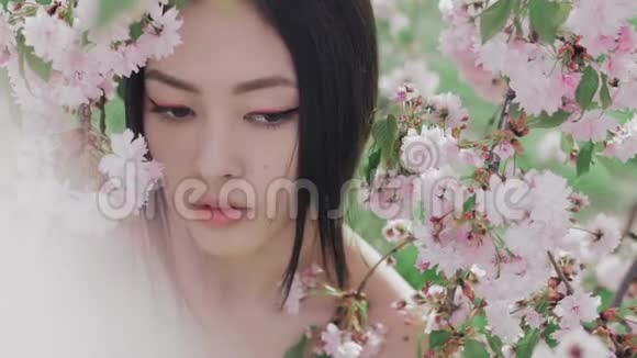 一个美丽的亚洲女孩在户外与春天的花朵树的肖像视频的预览图