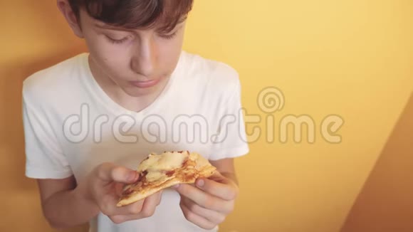 披萨快乐的青少年生活方式吃一片披萨的概念十几岁的男孩饿了吃一片披萨慢动作视频的预览图